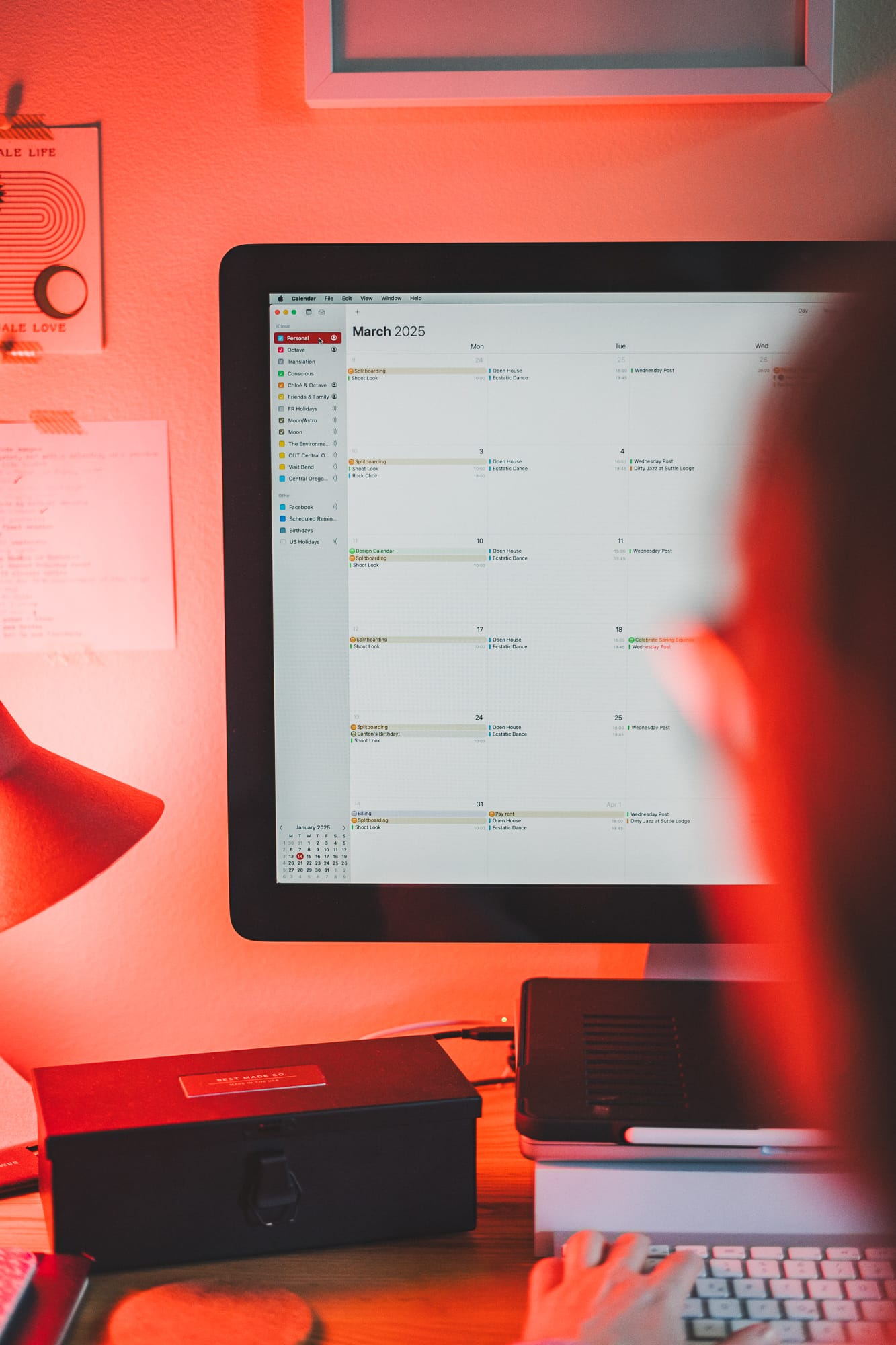 Image of a person at their computer, the screen shows the Apple Calendar app