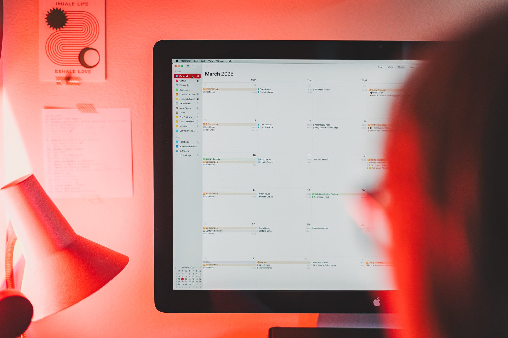Image of a person at their computer, the screen shows the Apple Calendar app