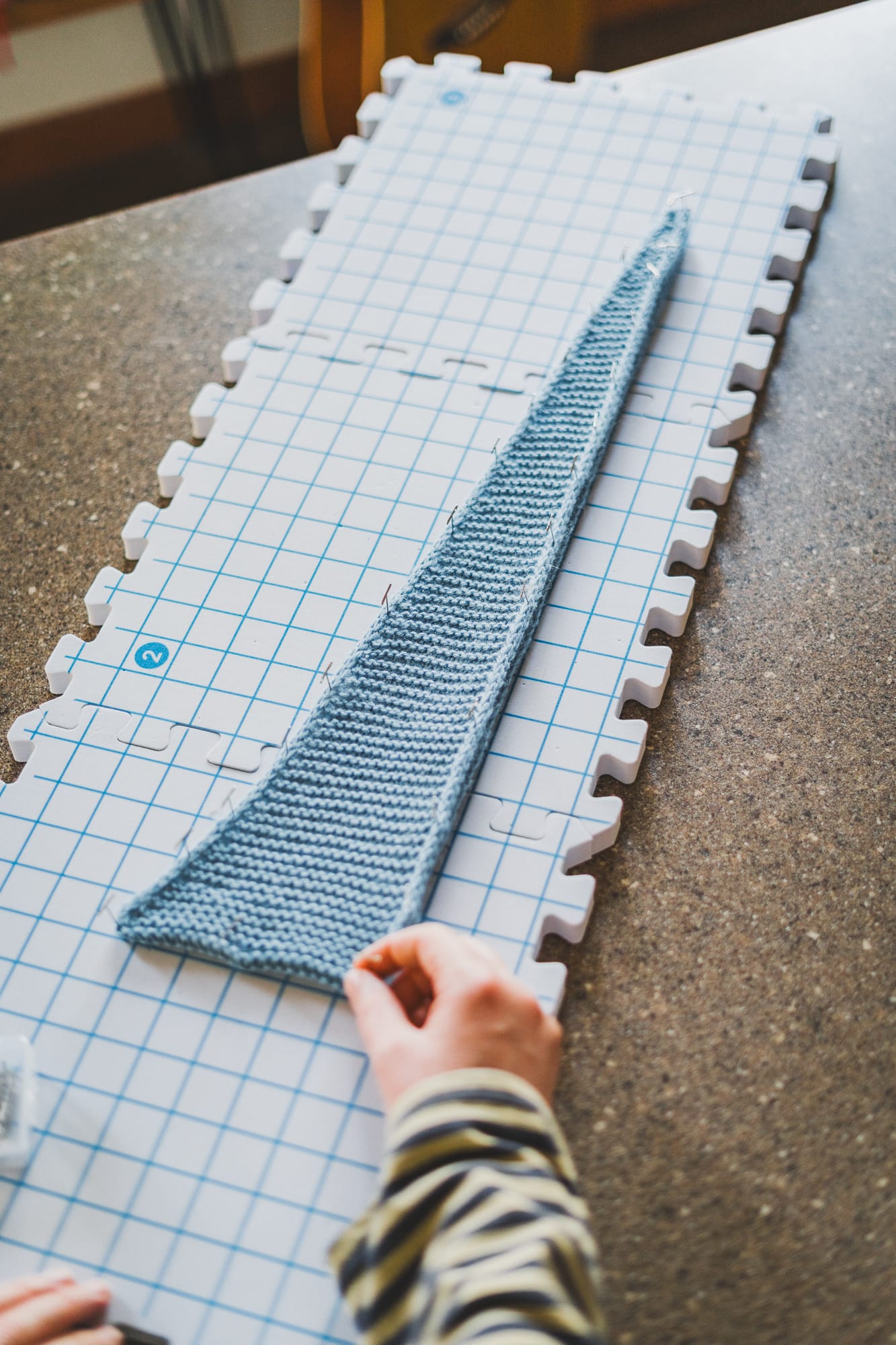 Light blue Sophie scarf pinned to foam blocking mats, stretched into its triangular shape during the blocking process.